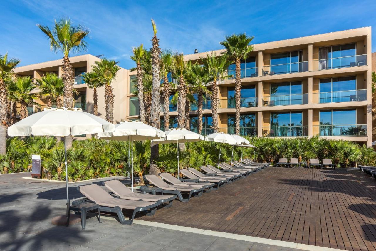 Ap Lago Montargil - Conference & Spa Екстериор снимка The photo shows a modern resort or hotel area featuring several lounge chairs lined up on a wooden deck. Each lounge chair is paired with a white umbrella, providing shade. In the background, there are palm trees, which add to the tropical atmosphere