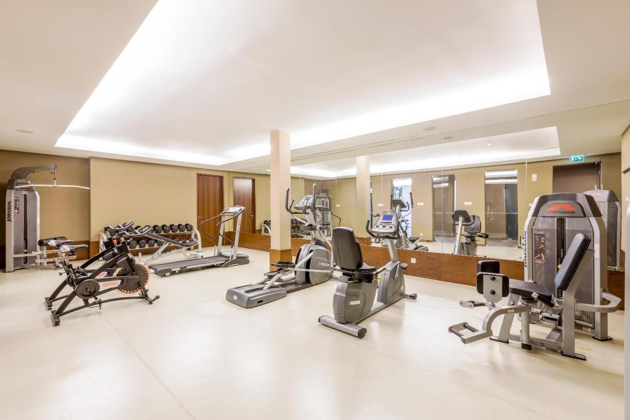 Ap Lago Montargil - Conference & Spa Екстериор снимка The image shows a modern gym interior featuring various exercise equipment. On the left, there are free weights and weight benches. In the center, there are multiple machines, including a stationary bike and an elliptical. The space is well-lit with 