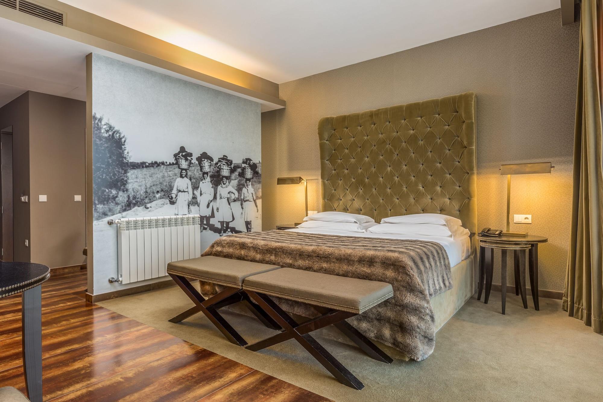 Ap Lago Montargil - Conference & Spa Екстериор снимка The photo shows a modern hotel room with a large, plush bed that has a tufted, green headboard. The bedding is white with a textured blanket at the foot of the bed. A decorative wall behind the bed features a black and white mural of children in a fi