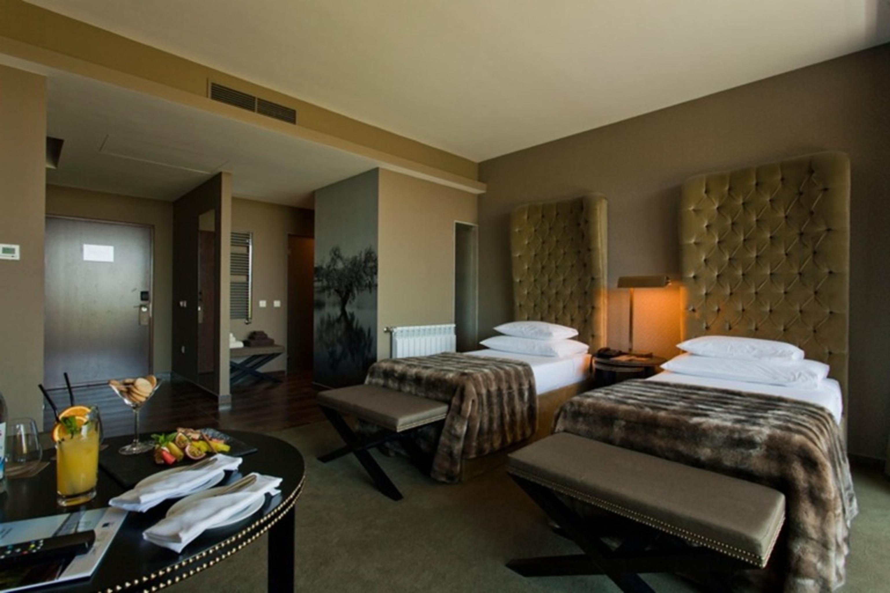 Ap Lago Montargil - Conference & Spa Екстериор снимка The photo shows a stylish hotel room featuring two beds with plush, upholstered headboards. The room has a modern and elegant design, with earthy tones dominating the decor. A small round table is set up in the foreground, displaying a drink and some