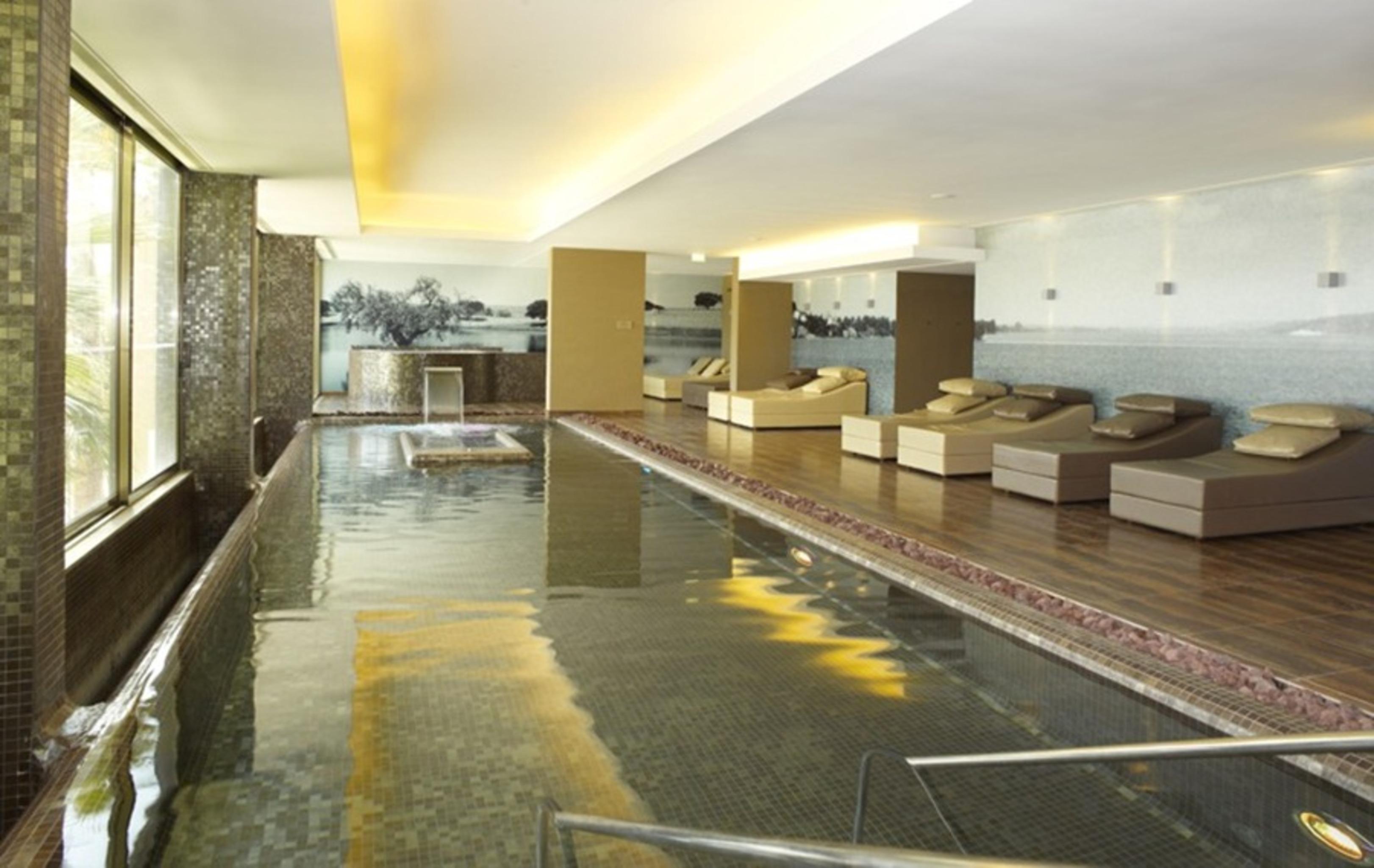 Ap Lago Montargil - Conference & Spa Екстериор снимка The photo shows a modern, serene spa environment. There is a swimming pool with calm water, reflecting the surrounding decor. Along the sides, there are several comfortable lounge chairs arranged, perfect for relaxation. Large windows allow natural l