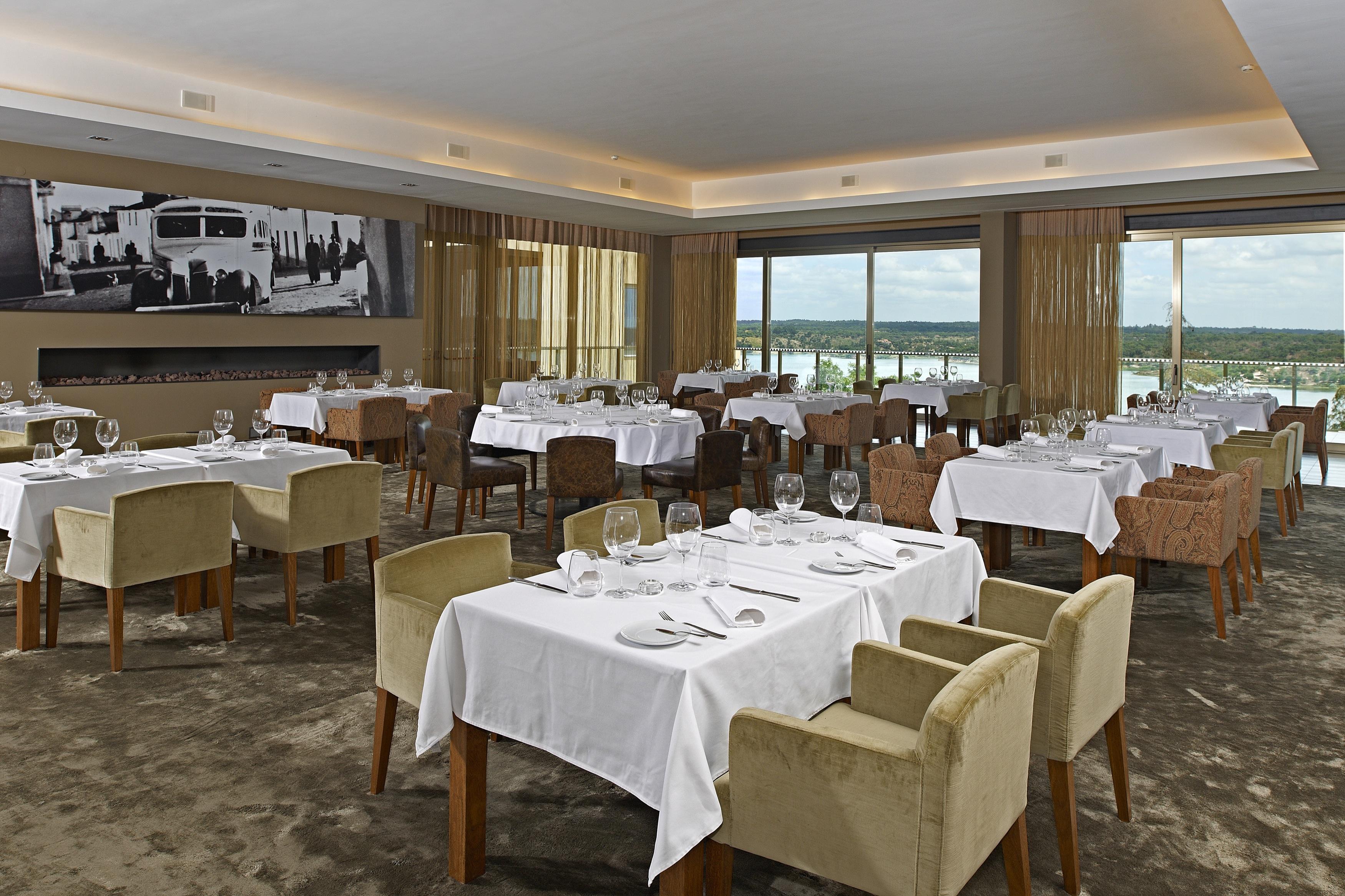 Ap Lago Montargil - Conference & Spa Екстериор снимка The photo shows an elegant restaurant interior featuring neatly arranged tables with white tablecloths. Each table is set with plates, cutlery, and glasses. The seating includes a mix of upholstered chairs in different colors—some light and others da
