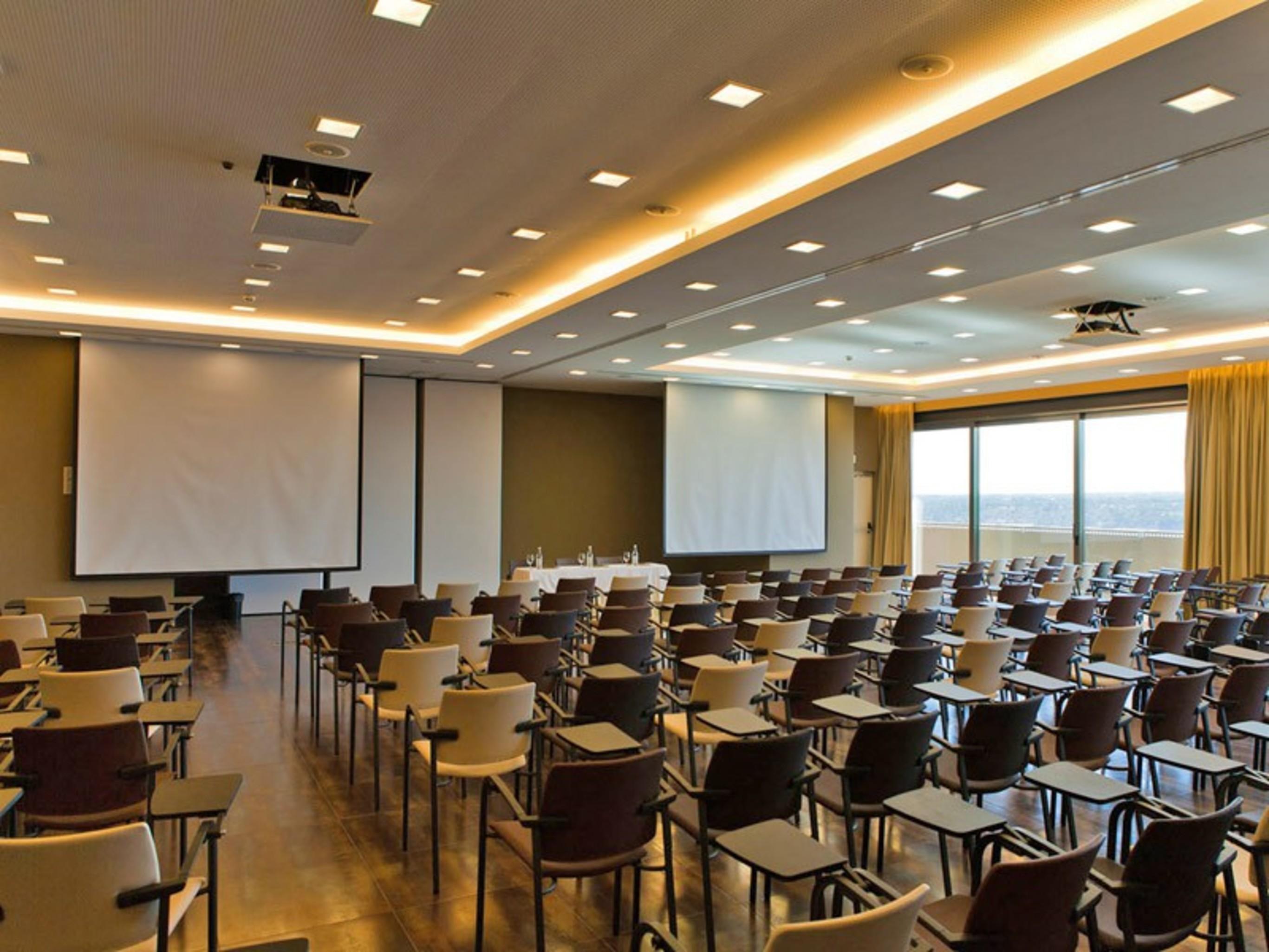 Ap Lago Montargil - Conference & Spa Екстериор снимка The photo shows a large conference room set up for a presentation or meeting. There are multiple rows of chairs arranged in a semi-theater style, facing two large projection screens. The room has a modern design, with soft lighting and large windows 